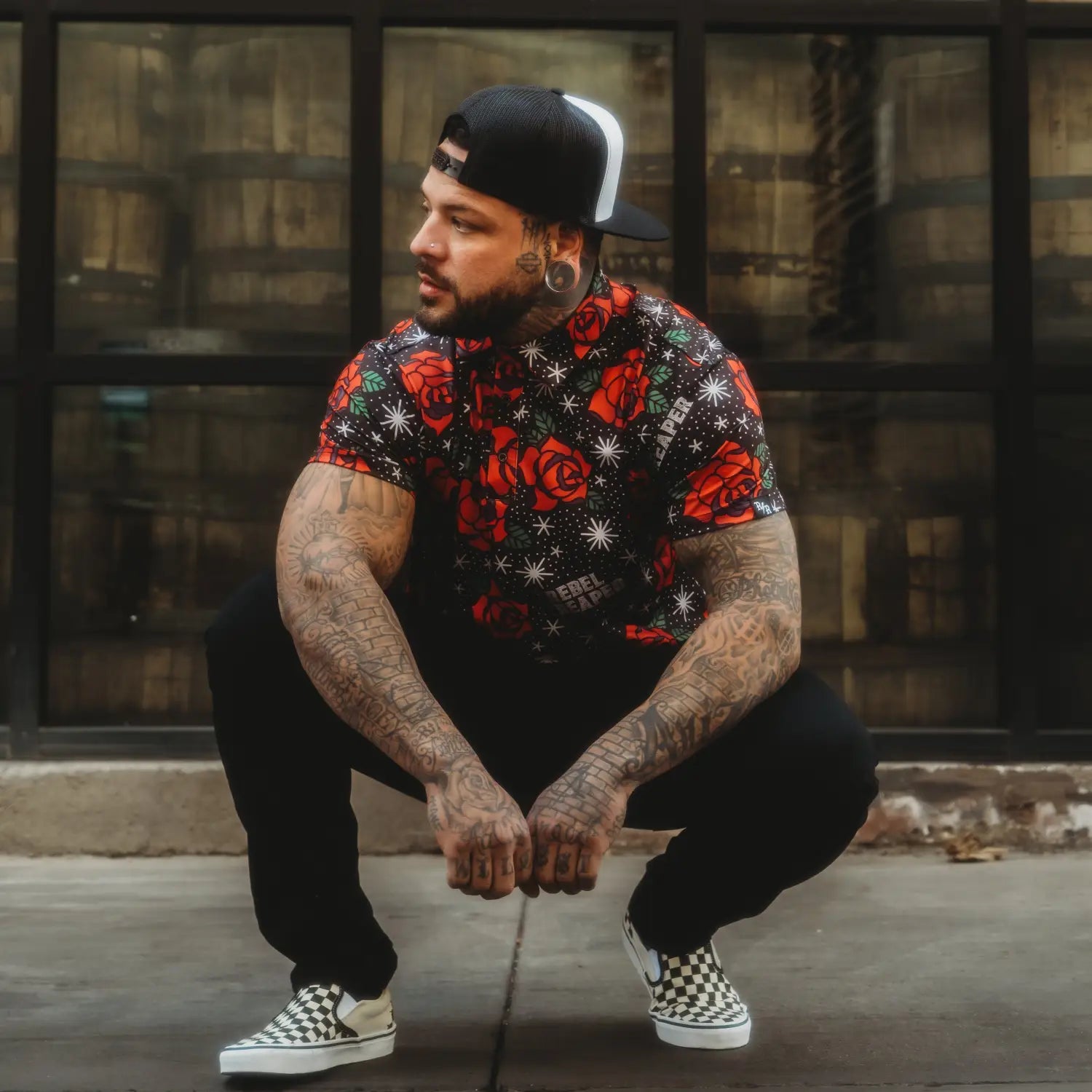 Man in floral shirt and checkered shoes wearing Flash of Roses Black Polo Shirt, a bold design polo for casual outings