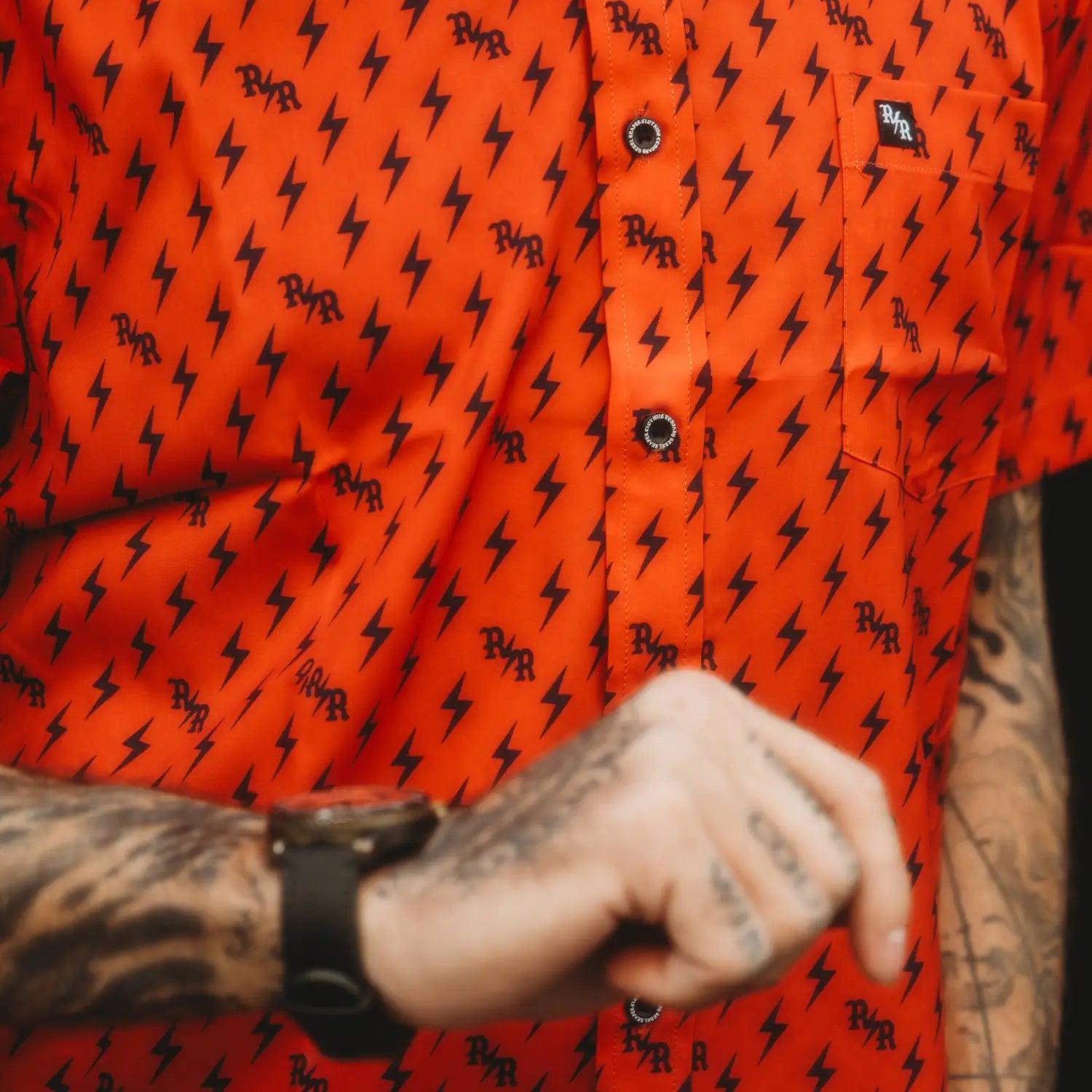 Orange shirt with black iconic bolts, hidden collar buttons, and wrinkle-resistant fabric