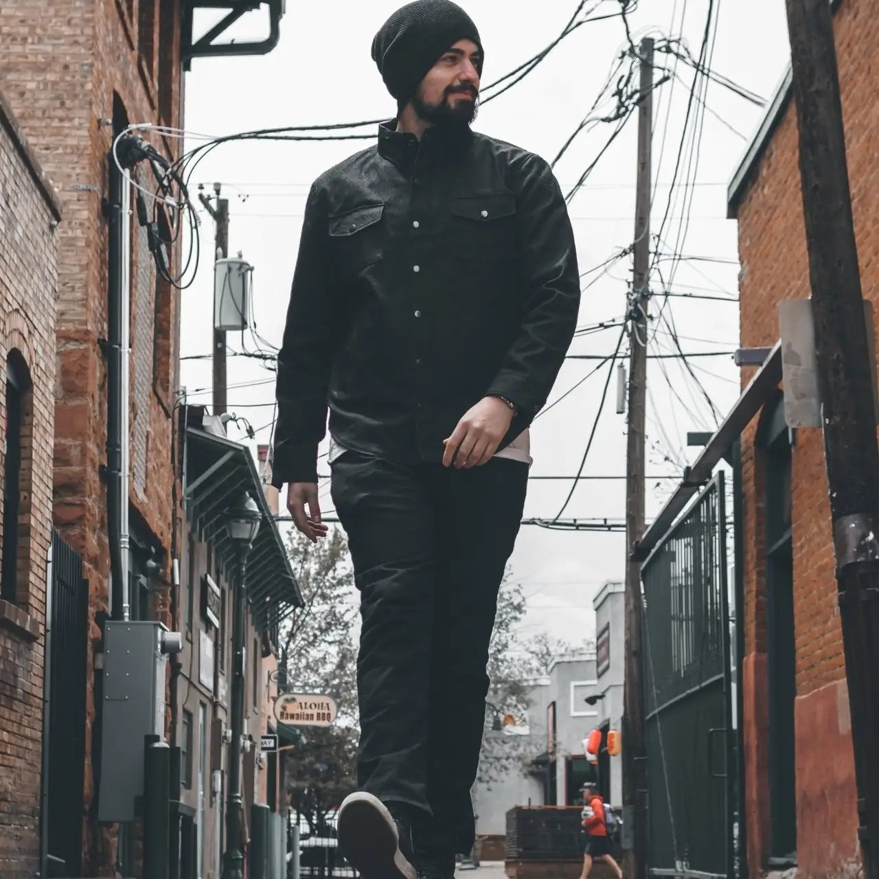Man in black clothing showcasing versatile chino pants with hidden pocket and branded buttons