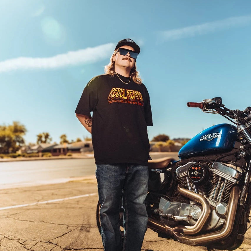 Man standing beside motorcycle wearing Rebel Reaper pants in the Pants & Shorts collection