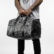 Person holding a black and gray patterned duffel bag against a white background