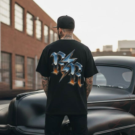 Man standing next to a classic black car with a brick building in the background