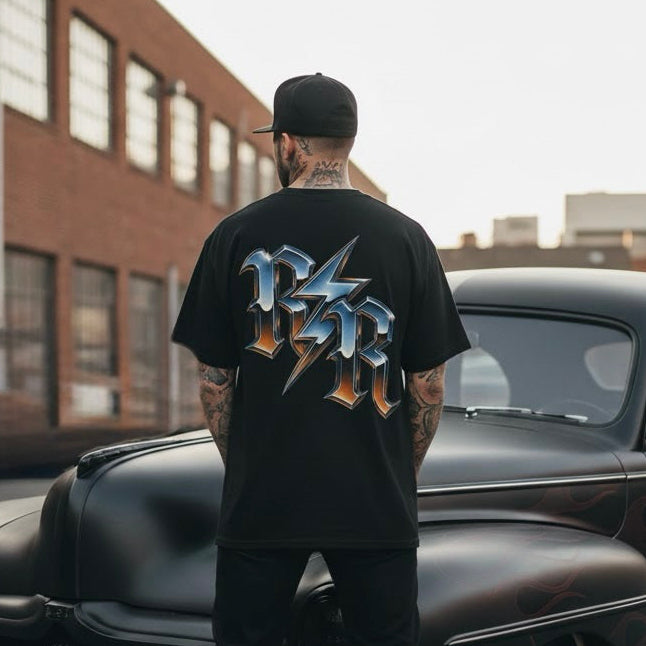 Man standing next to a classic black car with a brick building in the background