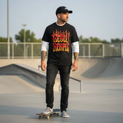 Man wearing a black t-shirt with 'Rebel Reaper' design at a skate park.