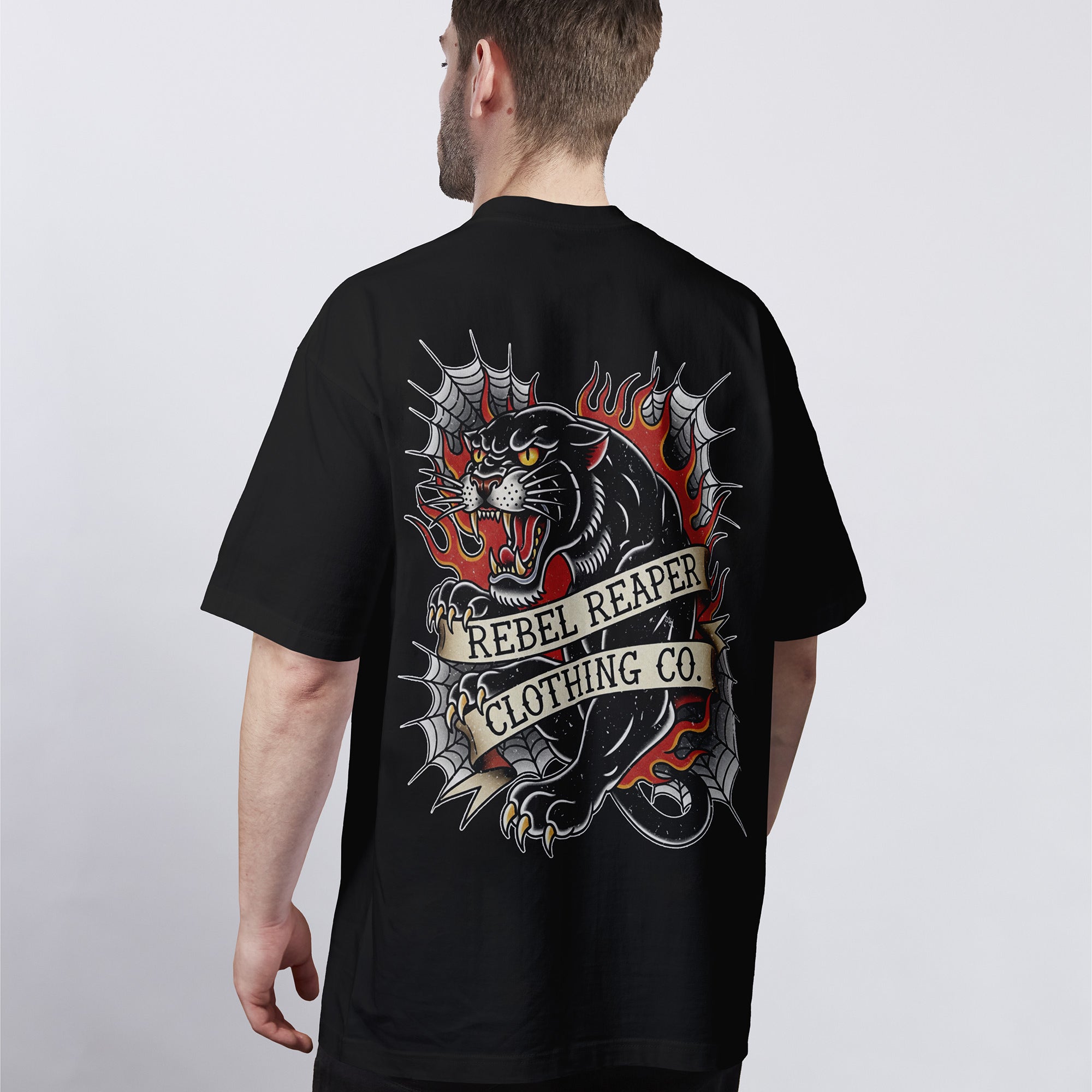 Man wearing a black t-shirt with a graphic design and 'Rebel Reaper Clothing Co.' text on the back.