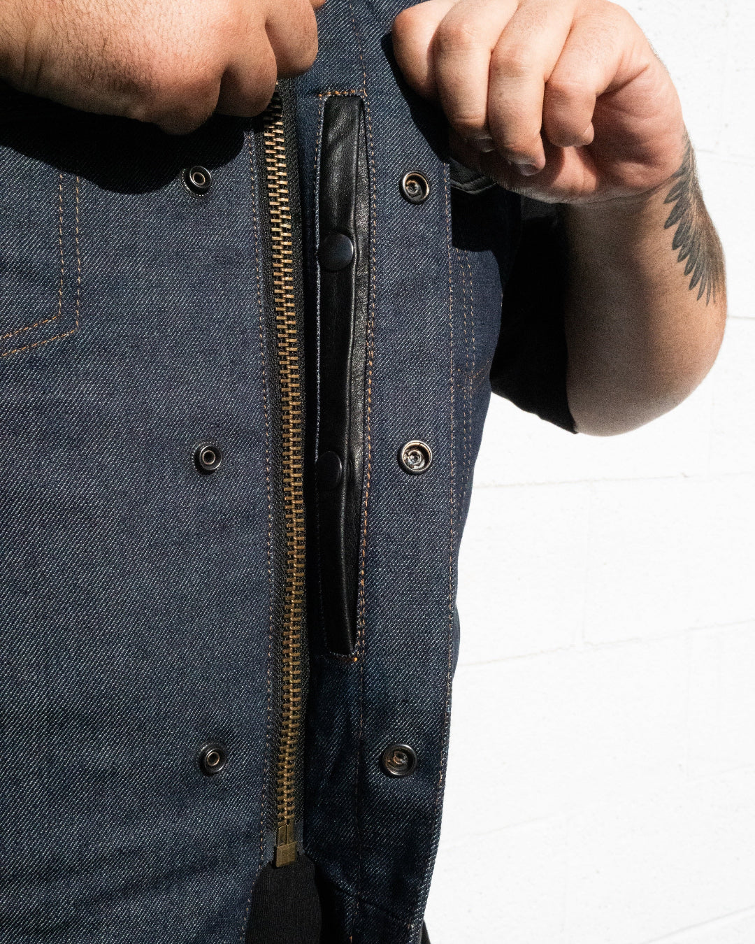 Close-up of a person wearing a blue denim jacket with a zipper, on a white background.