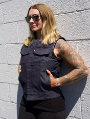 Person wearing a black sleeveless jacket against a gray brick wall