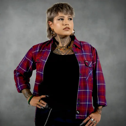 Person wearing a red and blue plaid shirt over a black top on a white background