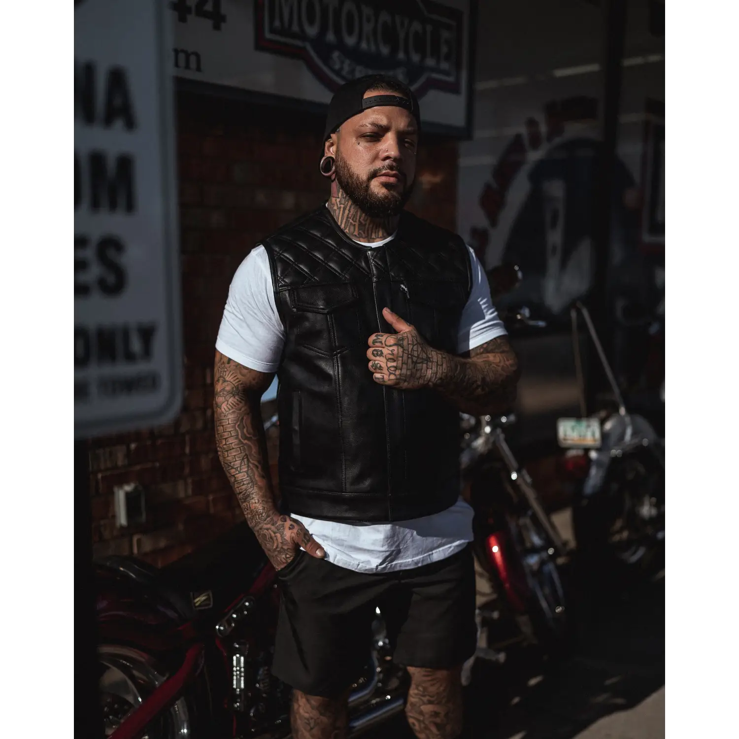 Tattooed man in black leather vest with concealed carry pockets and double diamond stitching