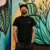 Tattooed man in Black Bamboo Button Up Shirt S/S with hidden collar buttons and wrinkle-resistant fabric