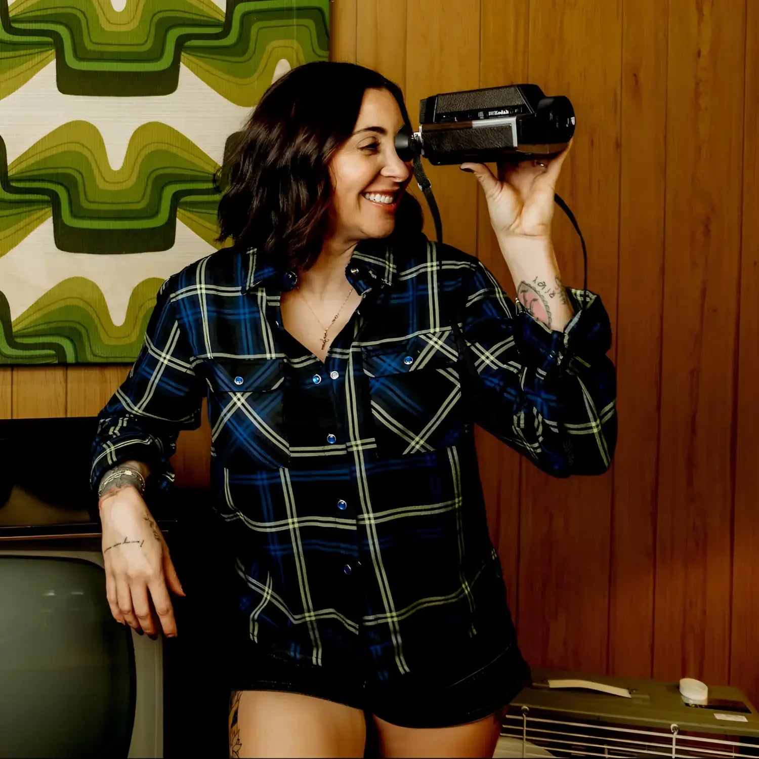 Woman holding a vintage camera in a room with retro decor