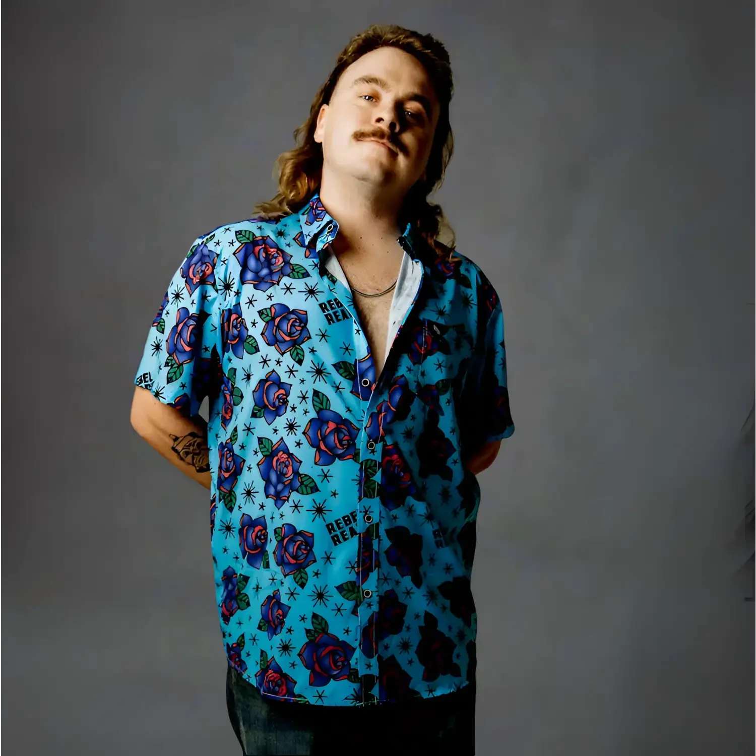 Man in blue short sleeve button-up shirt with bold purple roses from Blue Flash of Roses