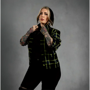 Person wearing a black and green plaid jacket with black pants on a white background