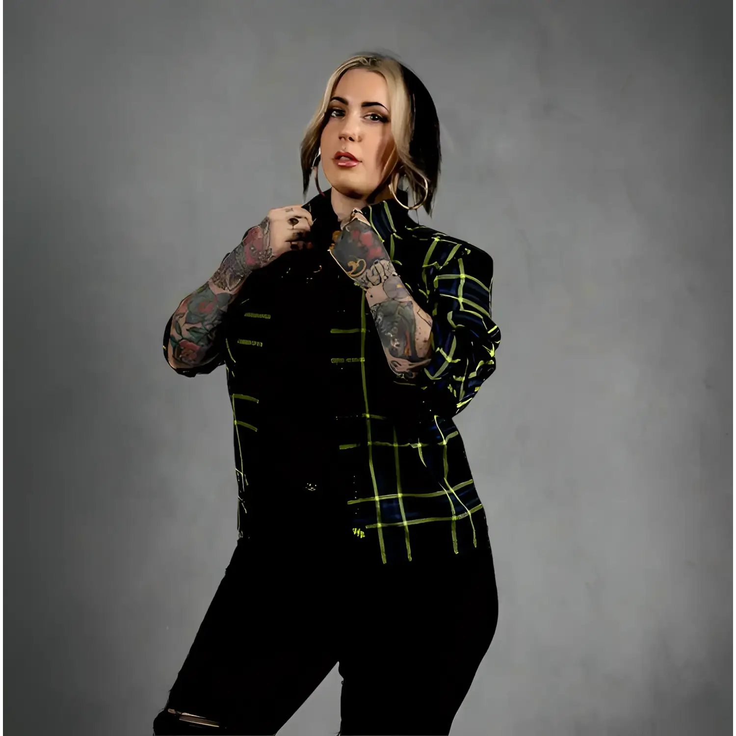 Person wearing a black and green plaid jacket with black pants on a white background