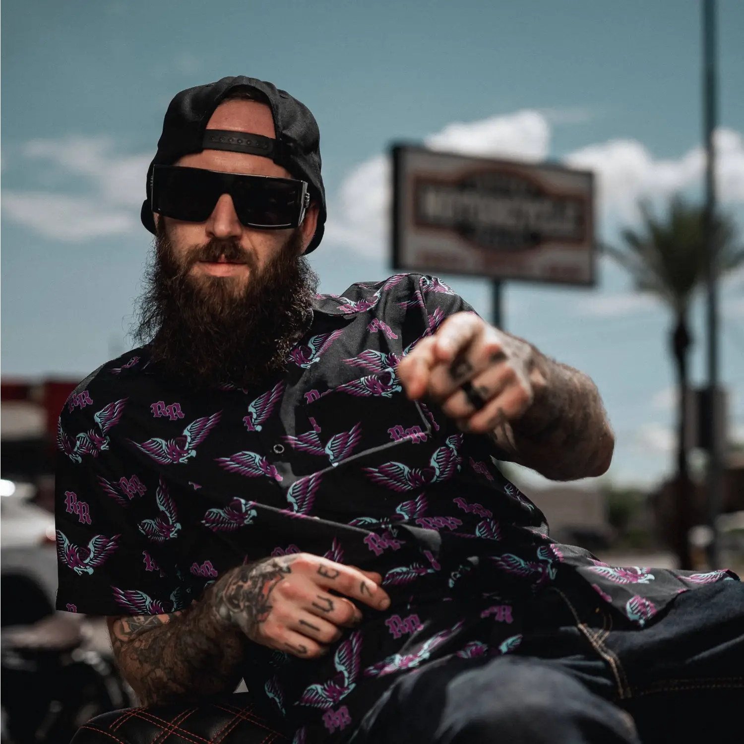 Bearded man in patterned shirt wearing Dana Retro Squared sunglasses with Rebel Reaper design and UV400 protection