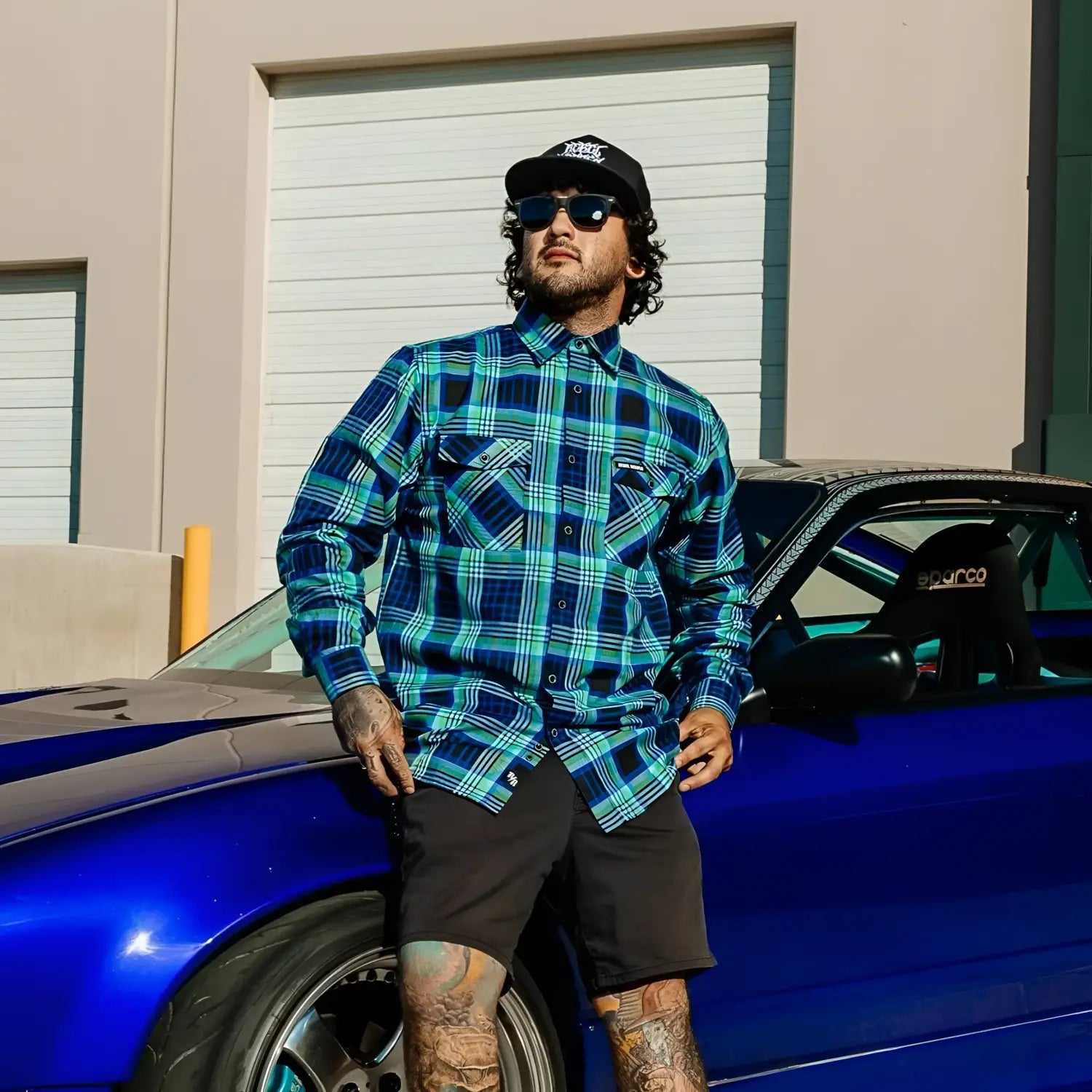 Man in plaid shirt leaning on blue car showcasing men’s Frostbite Flannel with durable fabric