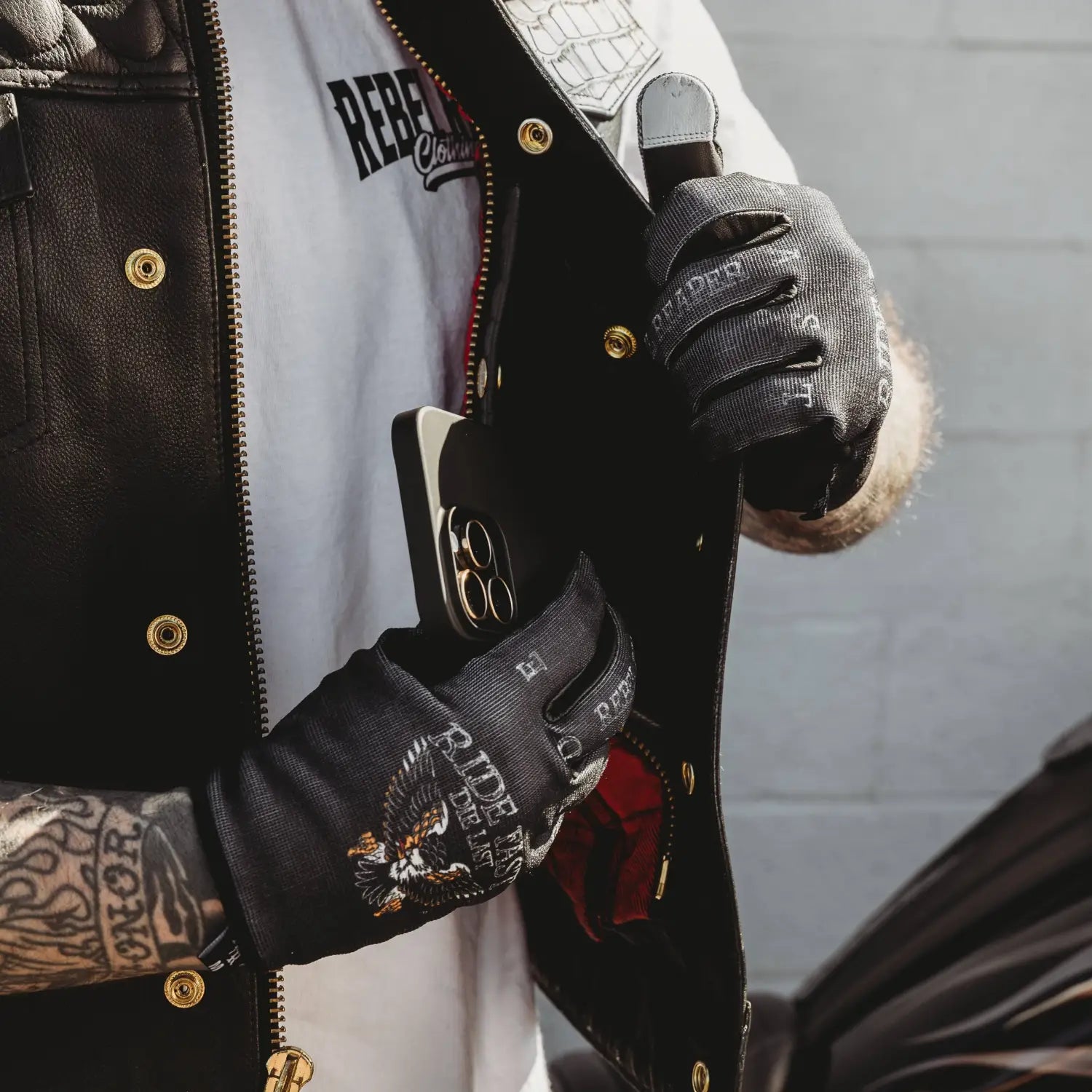 Black leather motorcycle vest displayed with Live Fast Eagle Moto Gloves for motorcycle enthusiasts