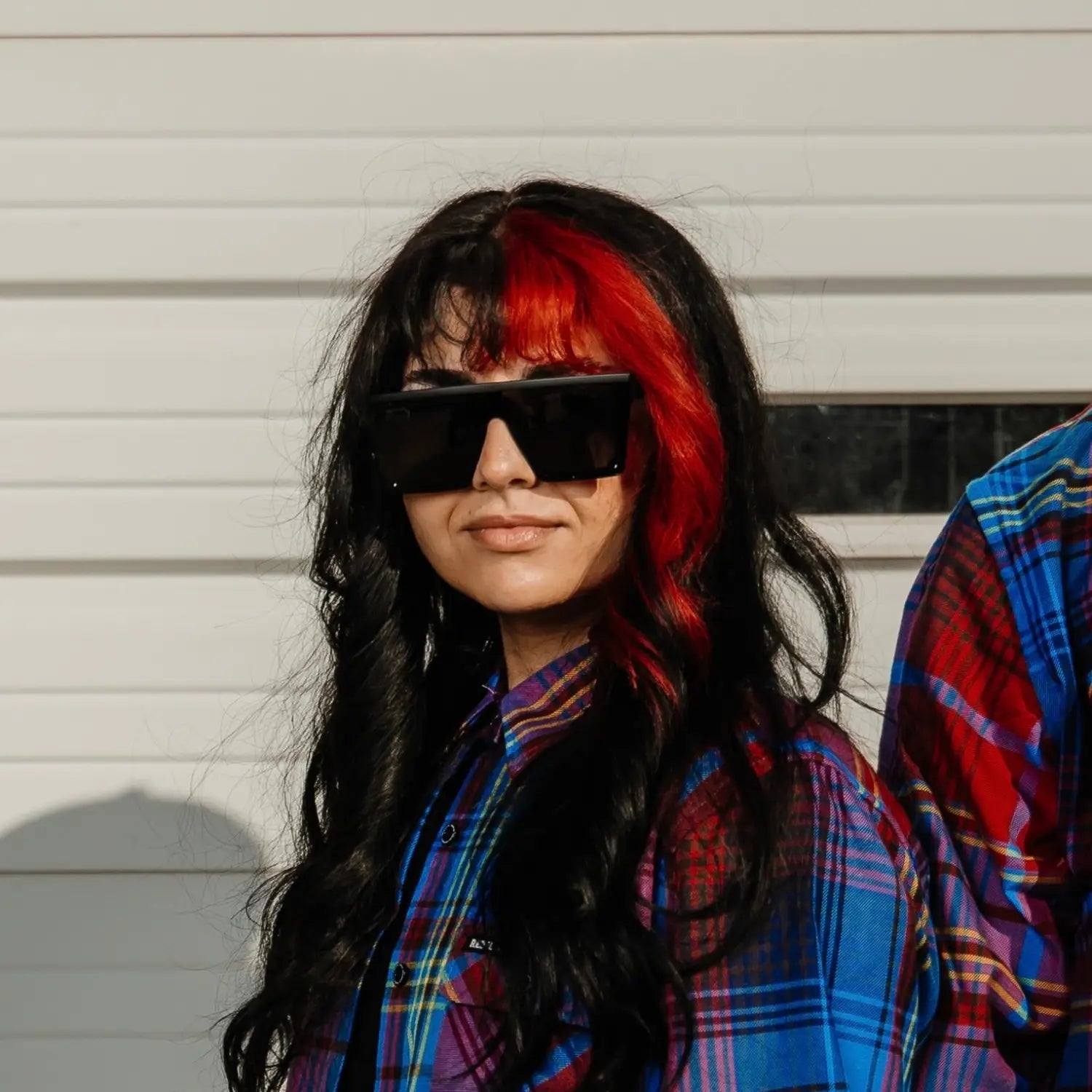 Person with red-streaked hair wearing oversized sunglasses from OG Square Reflective UV400 Sunglass Collection highlighting UV400 protection and durable black frame