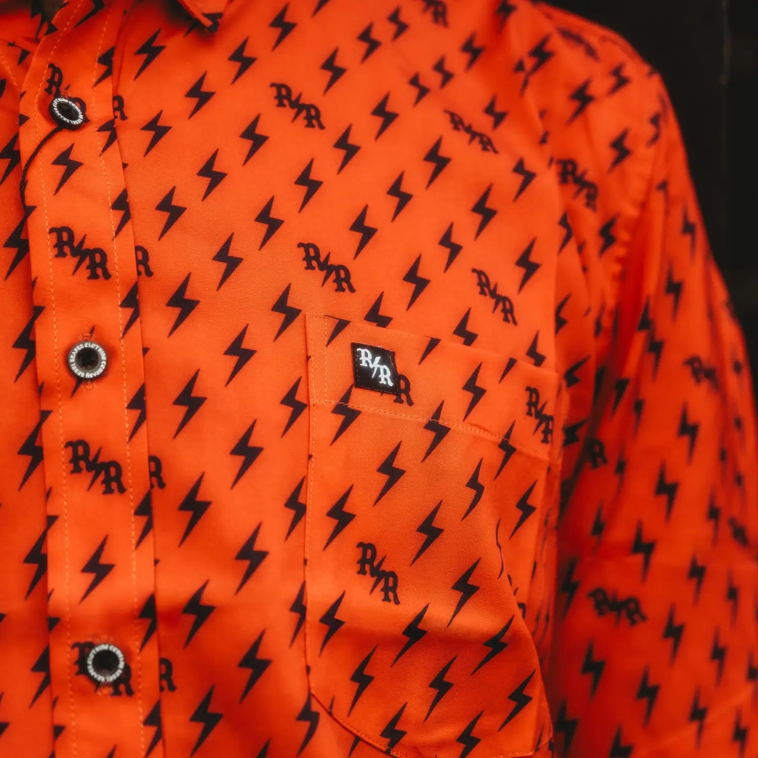 Orange shirt with lightning bolt pattern, iconic bolts, hidden collar buttons, wrinkle-resistant fabric